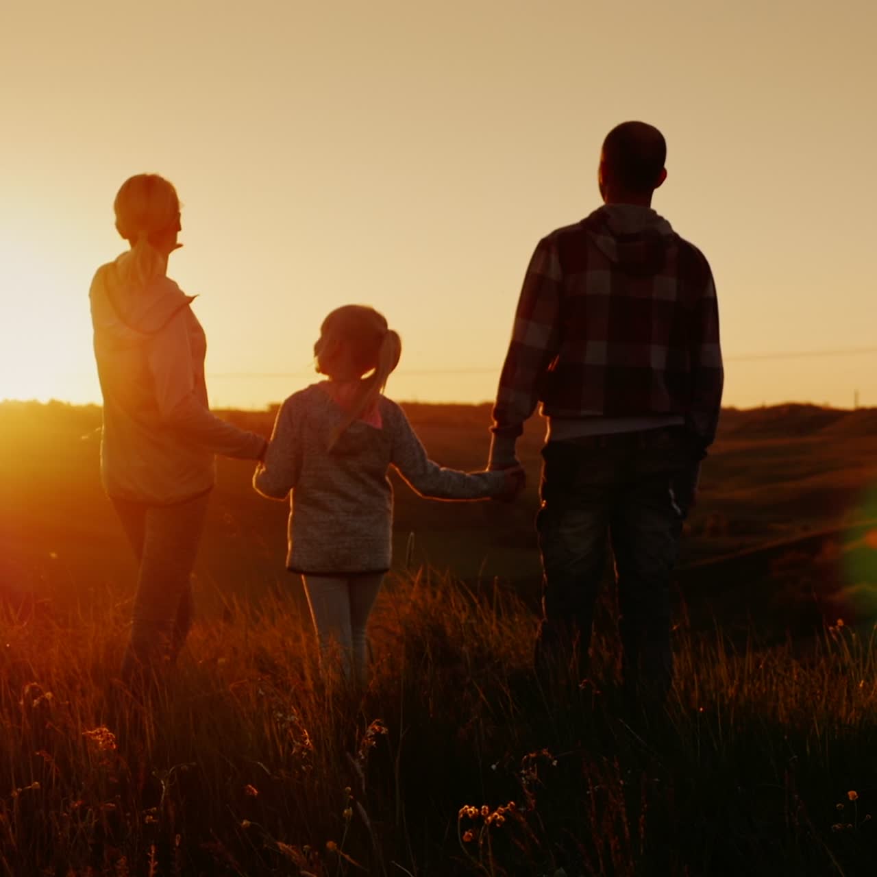 una pareja joven con un niño corriendo al aire libre en un lugar pintoresco al atardecer