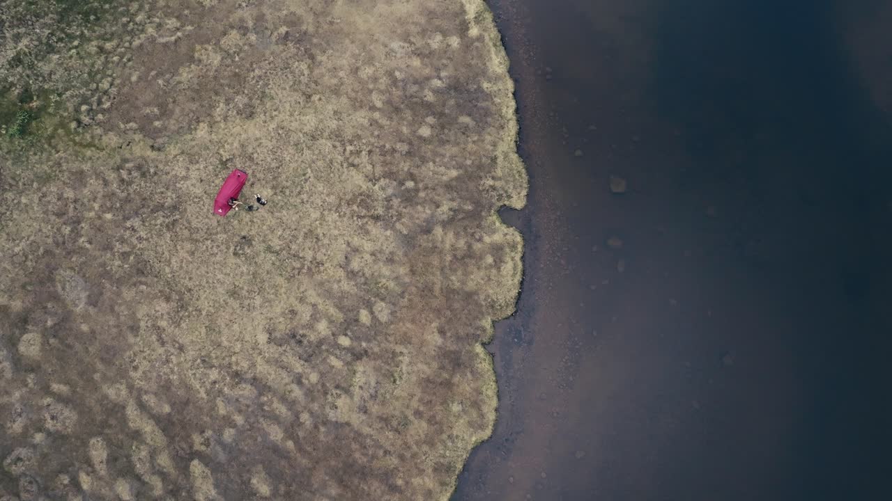 노르웨이 트론데라그 카운티 오센에 있는 내부 코오케르트조나 호수 연안에 세워진 캠핑 텐트 에서 한 남자와 그의 개가 휴식을 취하고 있다.