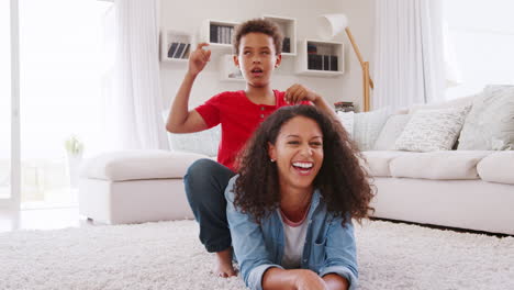 portrait of mother and son lying on rug and pulling faces at home
