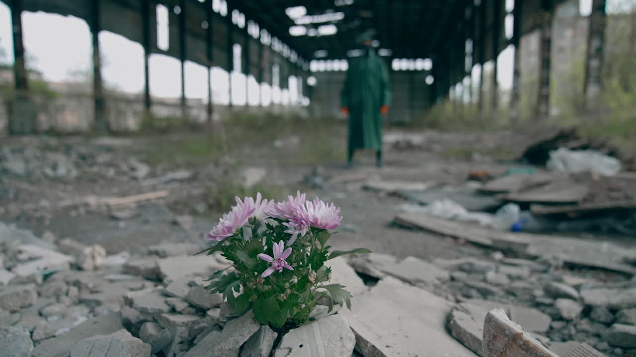 Nature in danger. Ecologist in safety suit and gas mask placing flowers in abandoned place. Biochemical attack and polluted environment concept