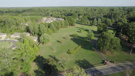 Aerial-over-neighborhood-park,-lush-trees,-wealthy-houses,-trail