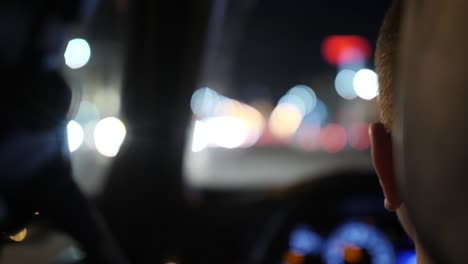 the driver is driving a car. night road and highlights of passing cars. close-up. view from the rear seat. 4k slow motion