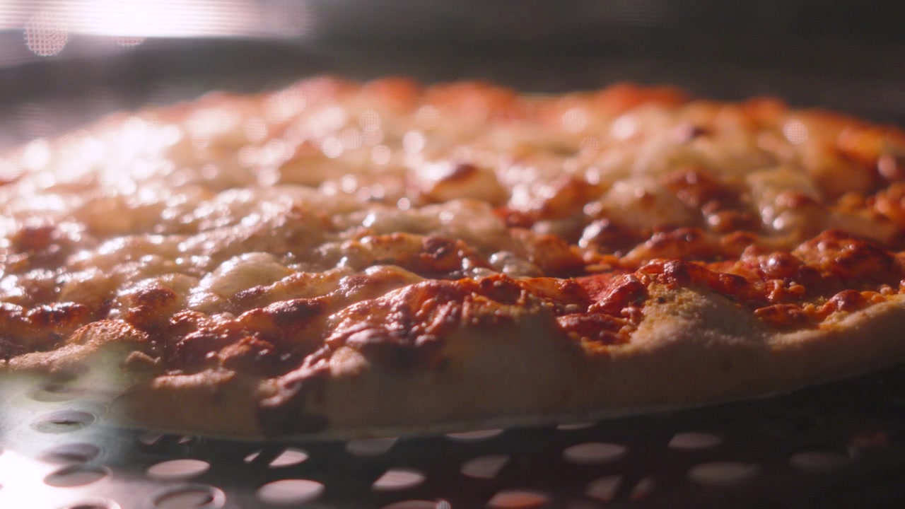 Pizza al formaggio e pomodoro che sobbolle lentamente mentre cuoce nel forno. Mozzarella filante fusa su crosta sottile.
