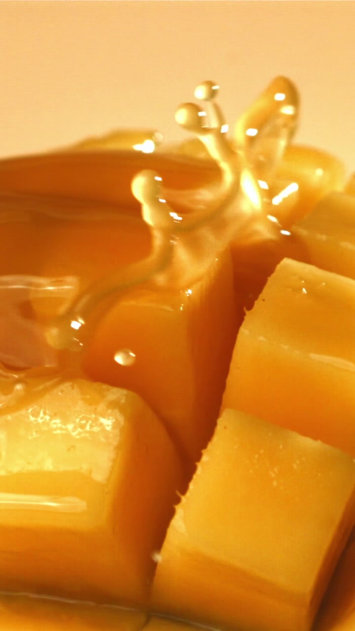 Sciroppo dorato che cola su mango fresco tagliato