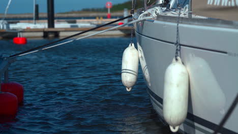 Nahaufnahme-Von-Kotflügeln,-Die-An-Der-Seite-Der-Yacht-Hängen,-Die-An-Einem-Sonnigen-Tag-Im-Yachthafen-Festgemacht-Ist