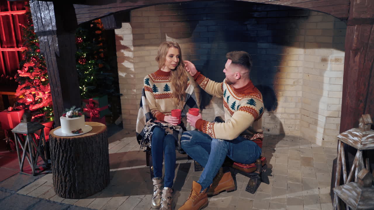 Young couple warming near fireplace in the evening. Romantic atmosphere before winter holidays.