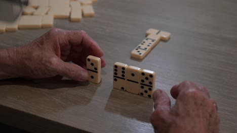 senior citizen playing dominoes places a domino on the table as his next game move