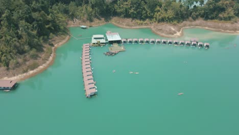 stunning drone footage of multiple people kayaking by the floating bungalows in khao sok national park thailand
