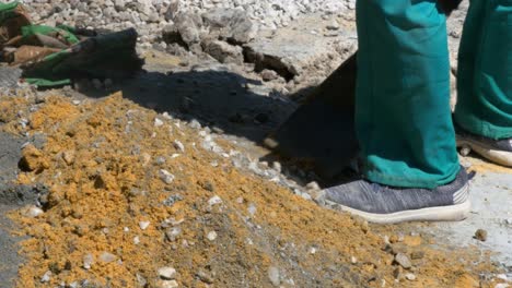 a young man mixing concrete with a spade on a windy day close up