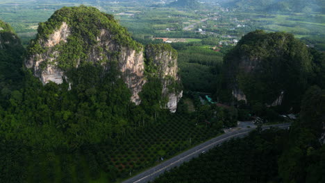 the scenic highway between palm trees and limestone mountains in krabi, thailand, drone shot