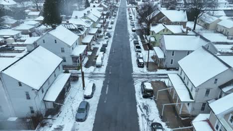 Aerial-birds-eye-flight-over-street-of-american-neighborhood-with-snowy-roofs-of-houses