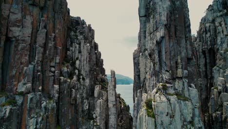 cape hauy drone flys in between columns in tasmania, australia