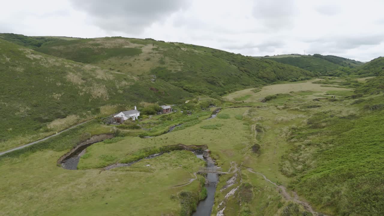 vista aérea de una remota cabaña de vacaciones ubicada en el campo rural rodeada de colinas y paisajes verdes