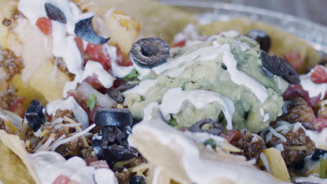 high speed shot of olives being dropped on loaded nachos