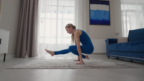 a woman at home does yoga exercises without leaving home. home training. a woman trains on the carpet in a blue suit