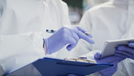 two technicians making notes in protective gloves