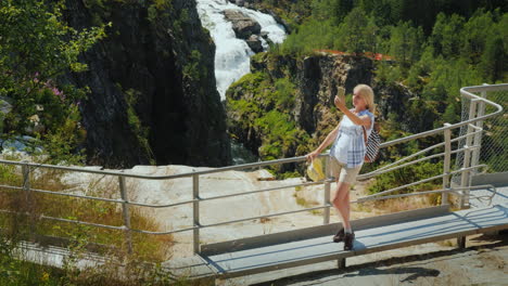 a woman looks at the majestic waterfall of woringsfossen in norway impressive beauty of scandinavian