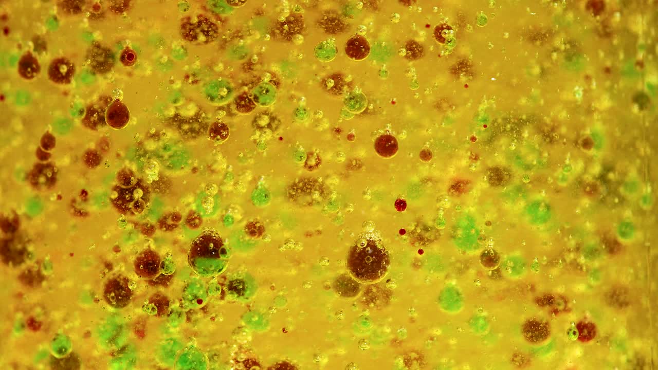 reacción química vibrante con gotas de colores en un vaso, mostrando el movimiento dinámico y la separación de sustancias