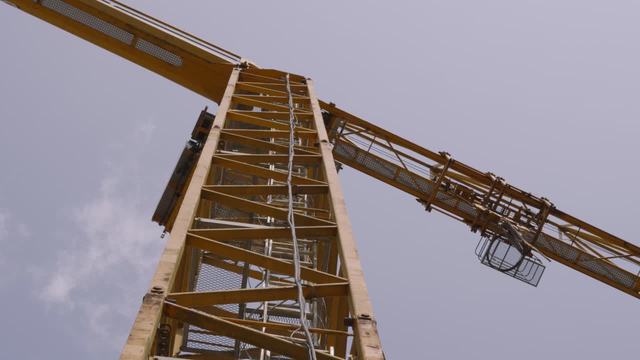 Vue imposante d'une grue avec câbles et cabine d'opérateur, prête à soulever de lourds objets pour l'industrie de la construction de bâtiments en 4K.
