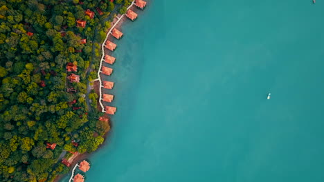 Toma-Aérea-De-Bungalows-Sobre-El-Agua-A-Lo-Largo-De-La-Costa-De-La-Selva-Tropical,-Langkawi,-Malasia