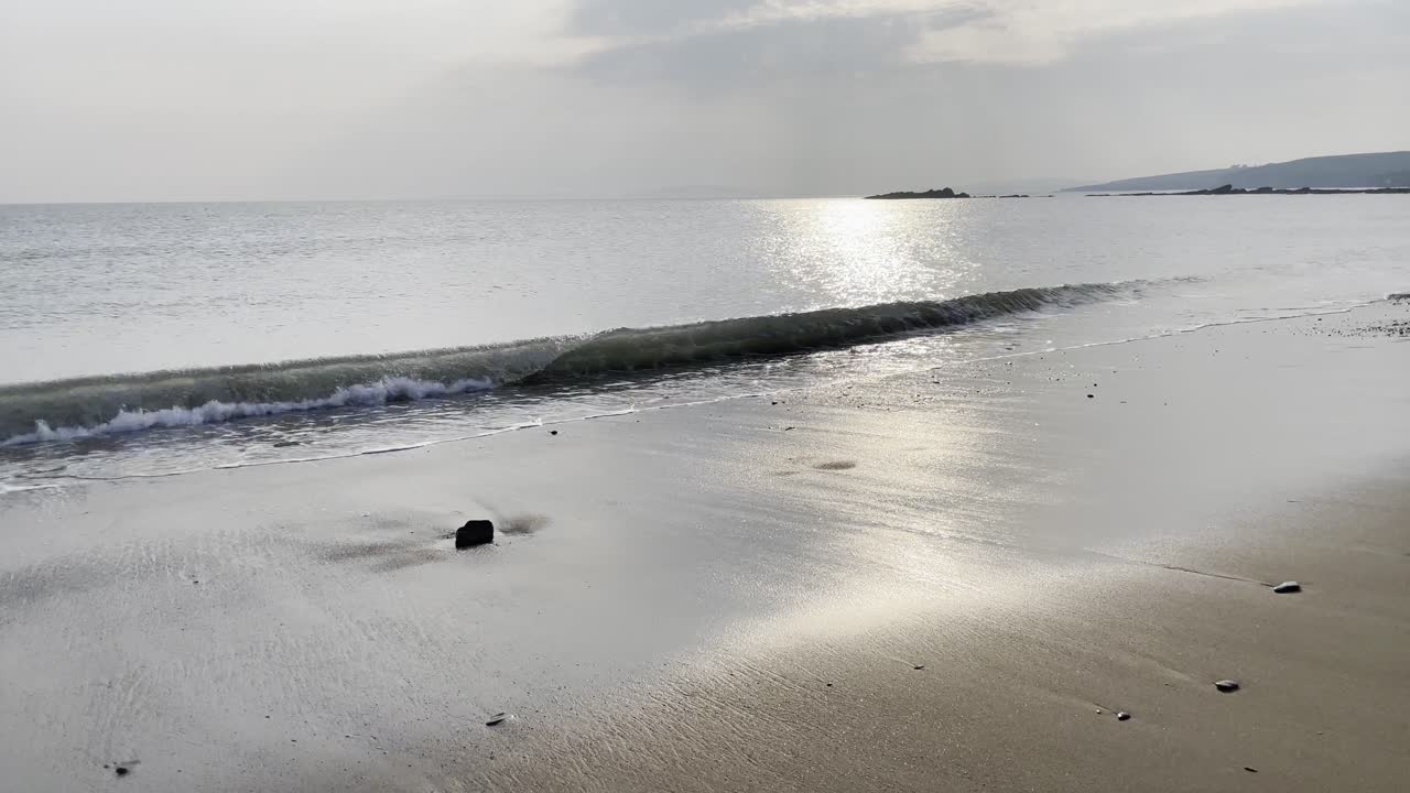 표면에 태양이 반사되는 파도와 모래사장