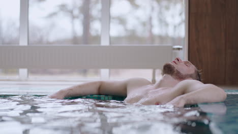 relax in thermal bath male visitor is lying in water of swimming pool and resting healthy lifestyle