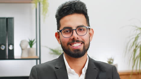 Portrait-of-happy-smiling-bearded-Indian-business-man-at-home-office-look-away-turn-head-at-camera