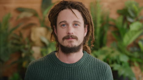 portrait of independent young man looking serious calm at camera wearing dreadlocks hairstyle bearded caucasian male blue eyes individuality real people series