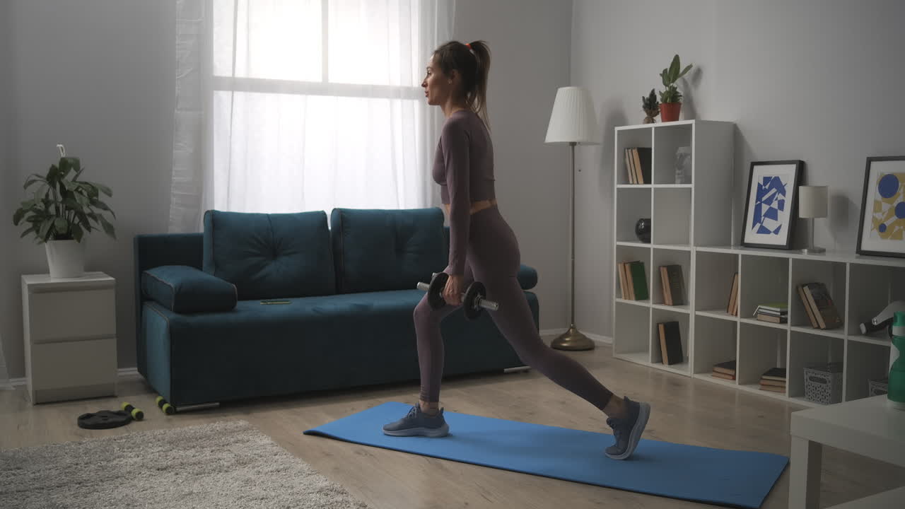uma jovem bonita com cauda de cavalo está agachada com halteres em casa exercícios para manter-se em forma e trabalhar os músculos das nádegas e pernas estilo de vida saudável