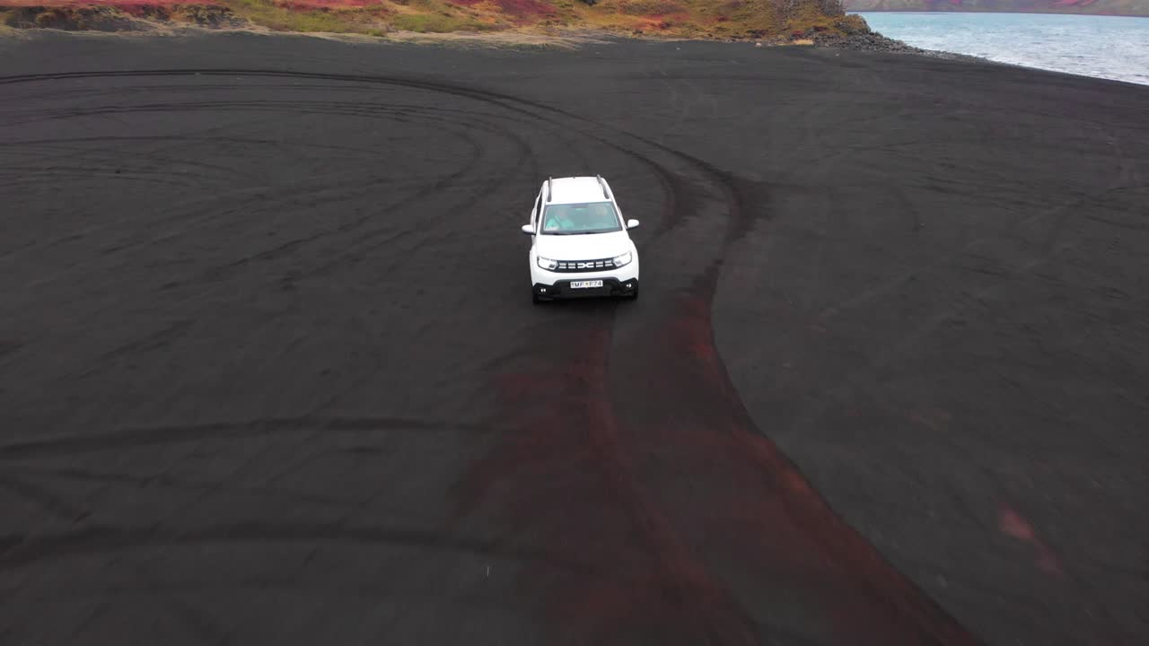 coche suv blanco conduciendo en la playa volcánica negra en otoño islandia
