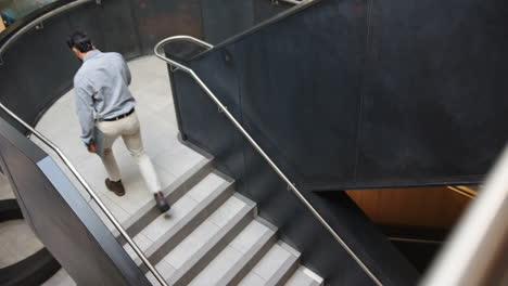 walking up stairs, businessman talking on smartphone in modern office building