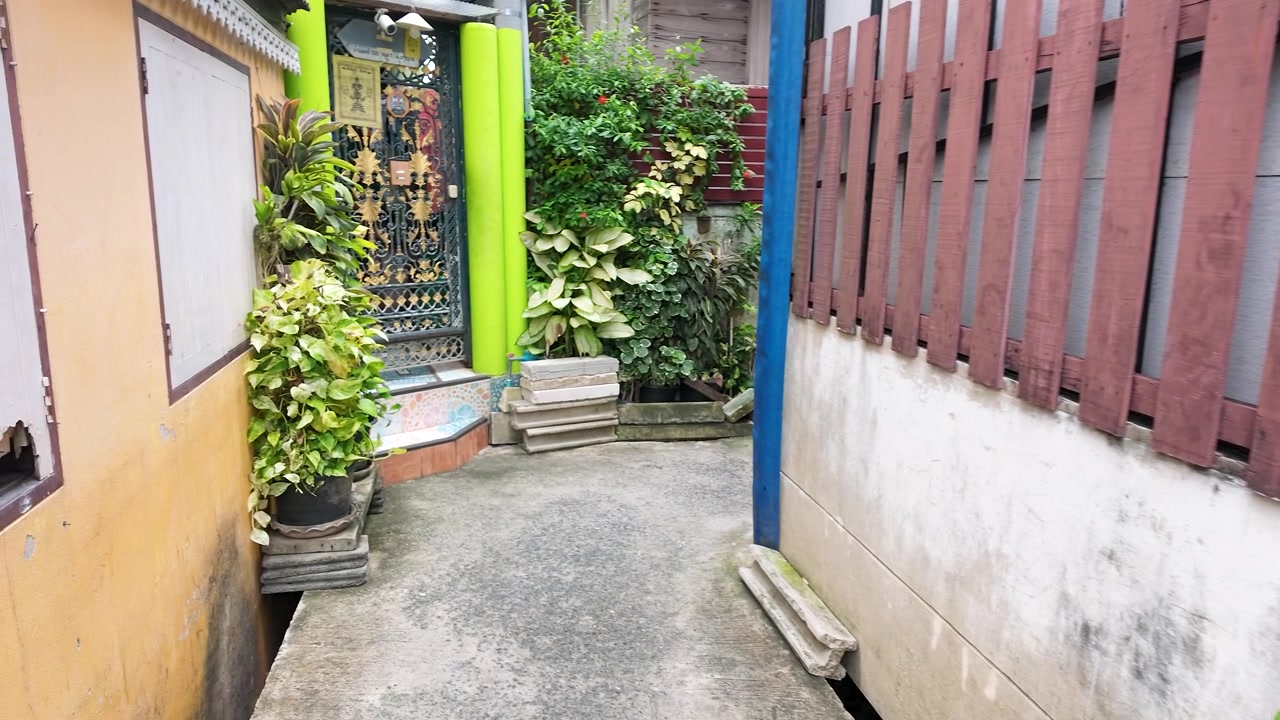 Handheld panning shot of clay pots and garden greenery along a fence in Koh Kret.