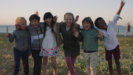 happy cheerful kids portrait of excited children group embracing celebrating enjoying seaside beach fun at sunset waving