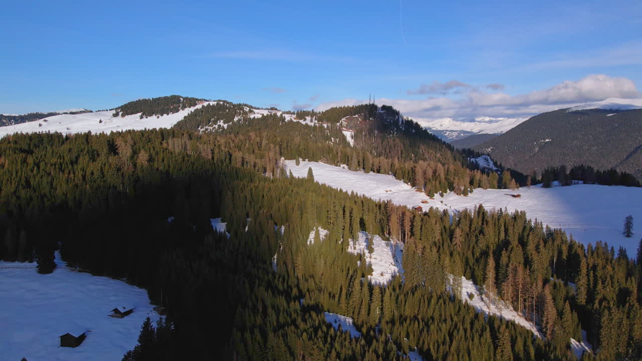 vista aérea de colinas y valles boscosos cubiertos de nieve bajo un cielo azul claro, mostrando la belleza serena de un paisaje de invierno
