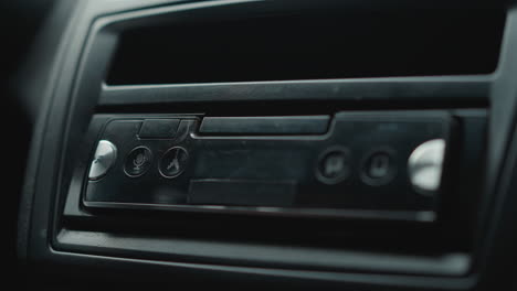 male hands tap touchscreen to tune music on car console infotainment display with glowing icons and tactile buttons under soft cabin lighting highlighting dashboard trim and user interaction gesture