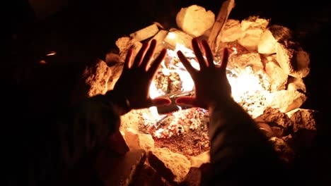 man warming hands by cozy bonfire during cold winter in europe, zoom out