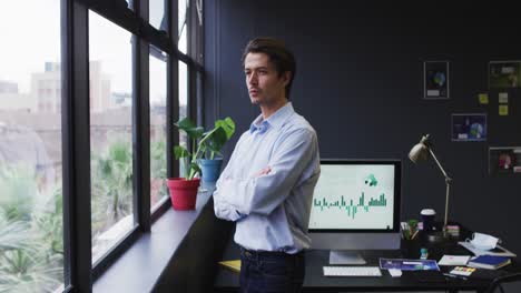 Caucasian-businessman-standing-looking-out-of-window-in-modern-office