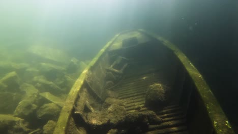 sunken wreck of a rowboat on the bottom of a flooded freshwater quarry with sunbeams coming from top