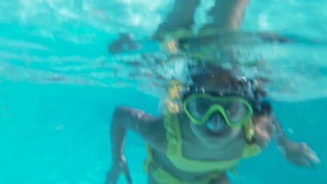 Happy-girl-in-goggles-swim-underwater-in-pool.-Close-up.