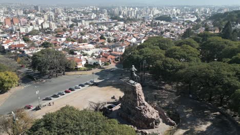 Aerial-view-of-General-Martin-Miguel-de-Guemes-memorial-monument-overlooking-the-city-of-Uruguay-under-gray-and-hazy-sky-due-to-pollution-and-climate-change,-Salta,-Argentina