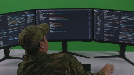 back view of bored asian man soldier developer write code with multiple computer screens in green screen studio