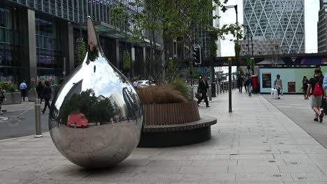 reflective teardrop sculpture in a modern urban environment