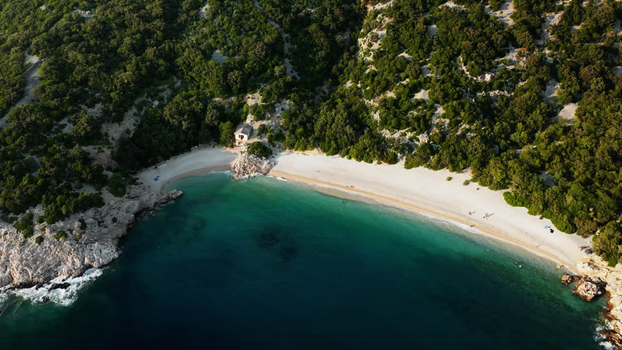 Drone che scende inclinando verso l'alto mentre le onde si infrangono sulla sabbia bianca della spiaggia di Lubenice, Croazia, splendida laguna