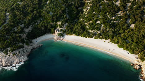 El-Dron-Desciende-Inclinándose-Mientras-Las-Olas-Rompen-En-La-Arena-Blanca-De-La-Playa-De-Lubenice-Croacia,-Hermosa-Laguna