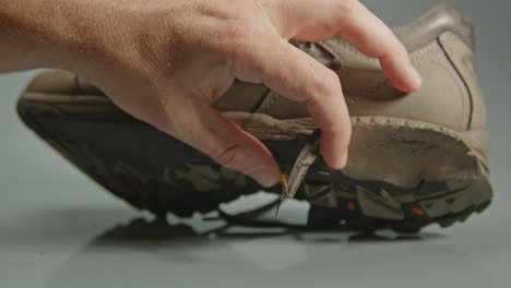 Hand-placing-worn-out-hiking-boot-on-table-and-showing-the-torn-shoe-soles