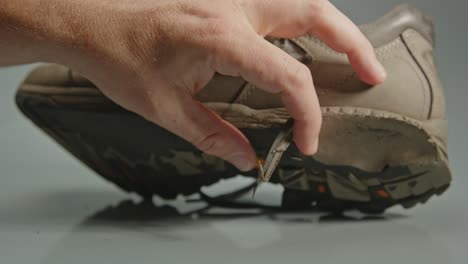 hand placing worn out hiking boot on table and showing the torn shoe soles