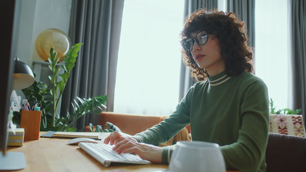 Jonge Aziatische vrouw werkt thuis op een desktopcomputer