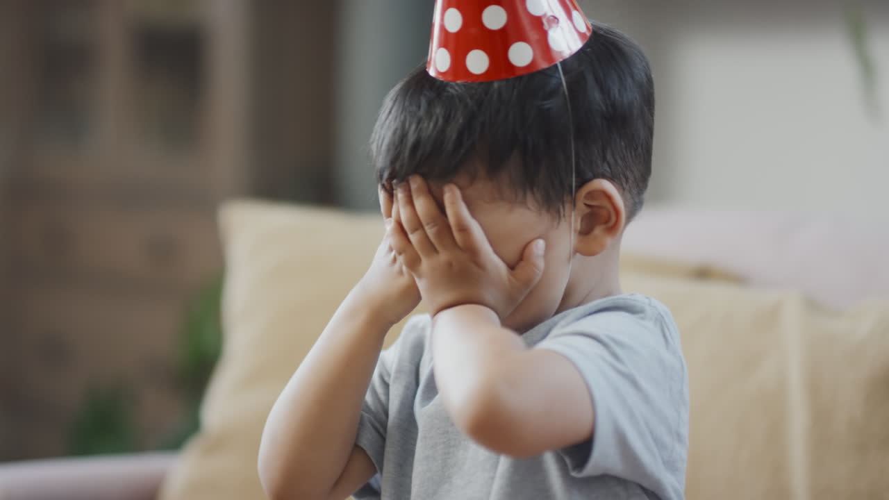 Asian Birthday Boy Blowing Out Candles on Cake