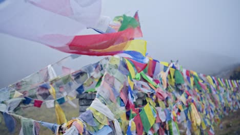 banderas de oración budista en las montañas brumosas de nepal, banderas de oración tibetanas coloridas en la niebla en los himalayas soplando en el viento en annapurna, colorido símbolo religioso del budismo en la naturaleza