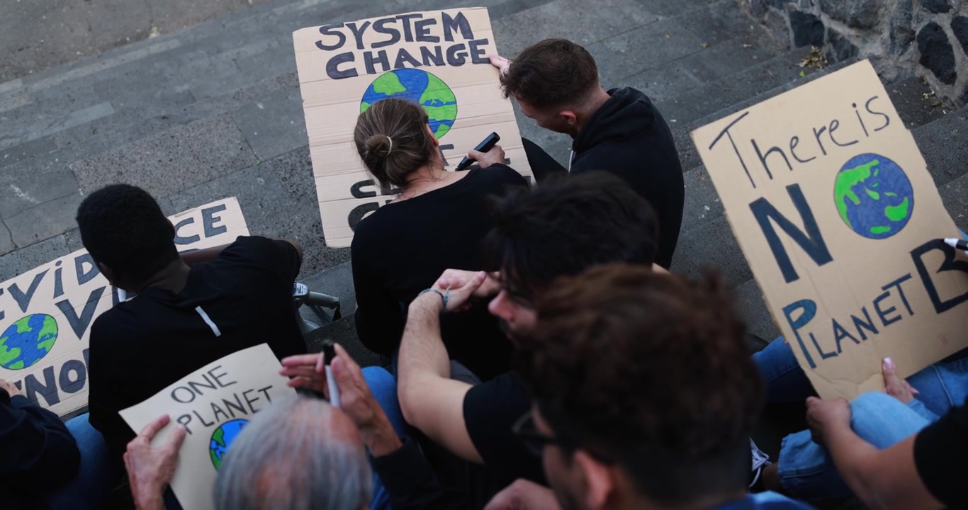 Gruppo eterogeneo di attivisti che protestano contro il cambiamento climatico con cartelli